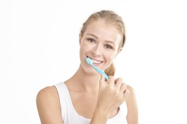 Kameraya bakarak ve gülümseyen dişlerini fırçalama güzel genç kadının Studio vurdu. Beyaz arka plan üzerinde izole. 