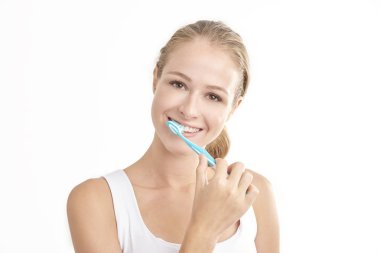 Kameraya bakarak ve gülümseyen dişlerini fırçalama güzel genç kadının Studio vurdu. Beyaz arka plan üzerinde izole. 