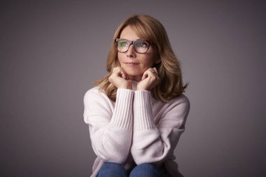 Orta düşünme Clos-up stüdyo portre gri bacgkround kopya alanı ile oturan kadın yaşlı. 