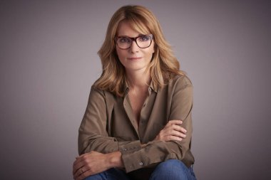 Stüdyo portre çekici orta yaşlı kadın kolları ile oturuyordu önünde açık gri renkli geçti. 