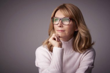 Orta düşünme Clos-up stüdyo portre gri bacgkround kopya alanı ile oturan kadın yaşlı. 