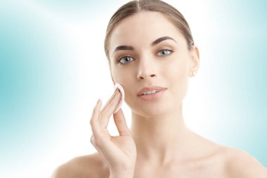 Pamuk yastık yüzü temizlik sırasında kullanarak güzel ve genç birbayan. Açık mavi renkli izole. Günlük rutin.