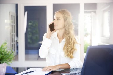 Ofis Masası oturma ve cep telefonu üzerinde biriyle konuşmak güzel genç iş kadını portresi