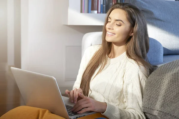 彼女のラップトップを使用して 自宅のソファに座って笑っている若い女性の肖像画 ホーム オフィス — ストック写真
