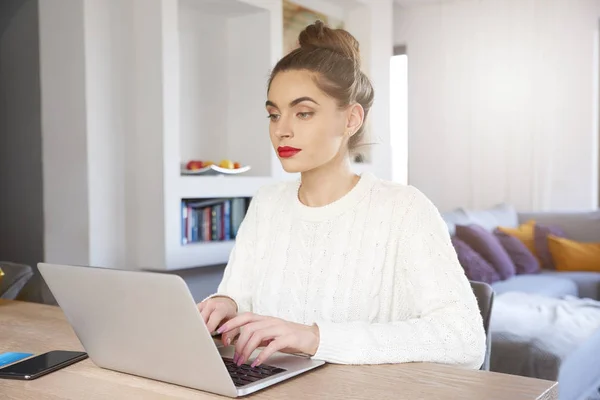 デスクに座っていると 自宅で仕事しながらノート パソコンのキーボードで入力する魅力的な若い女性の肖像画 ホーム オフィス — ストック写真