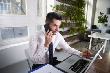 cep telefonundan konuşuyor ve laptop ofiste çalışan düşünme mali Yardımcısı işadamı.