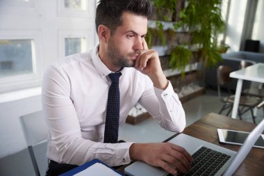 Düşünceli ise ofis masa başında oturan ve dizüstü bilgisayarda yazarak arıyor işadamı portre vurdu.