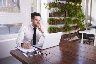 Düşünceli ise ofis masa başında oturan ve dizüstü bilgisayarda yazarak arıyor işadamı portre vurdu.