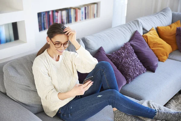 ソファとテキスト メッセージングでリラックスの美しい若い女性の全身ショット — ストック写真