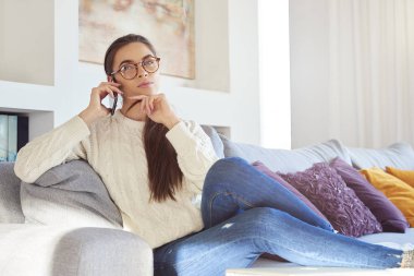 Cep telefonu kullanarak ve koltukta evde dinlenirken biriyle konuşmak güzel genç kadın portresi.