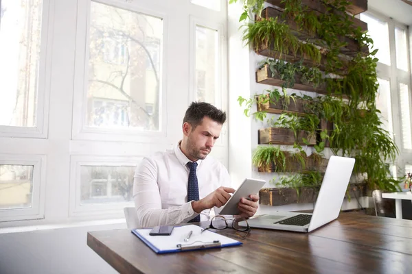 シャツとネクタイを身に着けていると 事務所の机に座って 新しいプロジェクトに取り組んでいる間デジタル タブレットを使用のビジネスマンを考えてください — ストック写真