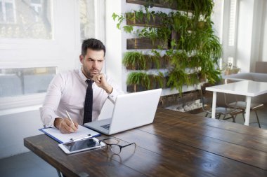 Düşünceli ise ofis masa başında oturan ve dizüstü bilgisayarda yazarak arıyor işadamı portre vurdu.