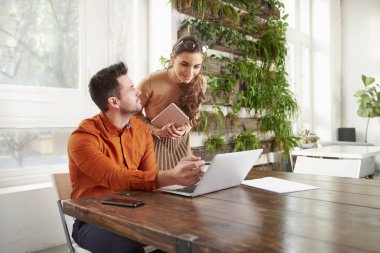 Satış adam ve onun gülümseyen Sekreter iş kadını birlikte dizüstü bilgisayarda çalışan bir kadeh. Ofiste iş toplantısı.