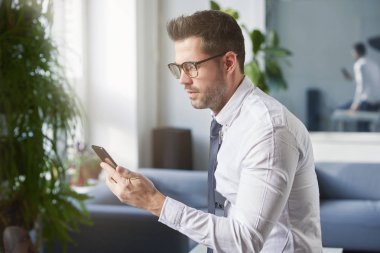 Onun cep telefonu ve kısa ofiste otururken mesaj kullanarak işadamı portre çekim. 