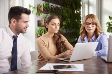 Ofiste takım çalışması. Dizüstü bilgisayar önünde onun meslektaşları ile oturma ve yeni iş planı hakkında danışmanlık genç mali asistanı iş kadını. 