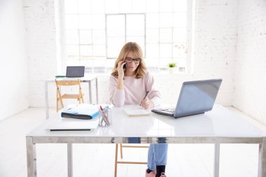 Ofis Masası oturma ve dizüstü bilgisayarda çalışırken arama yapma orta yaşlı çekici işkadını kadeh. 