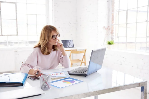 Portrait of financial consultant professional woman sitting at office desk and working on laptop.