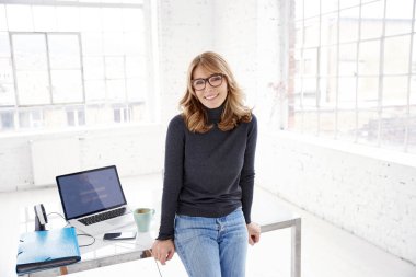 Ofiste ayakta ve size gülümseyen süre rahat kıyafetler giymiş orta yaşlı işkadını kadeh.