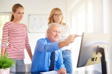 İş arkadaşları yeni mali rapor üzerinde çalışırken konuşuyor. Bilgisayar başında oturan ve bir şey iş arkadaşları için gösterilen üst düzey mali danışmanı. Ofiste takım çalışması. 