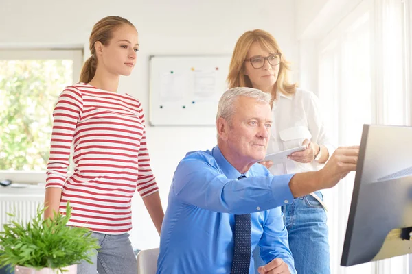 İş arkadaşları yeni mali rapor üzerinde çalışırken konuşuyor. Bilgisayar başında oturan ve bir şey iş arkadaşları için gösterilen üst düzey mali danışmanı. Ofiste takım çalışması. 
