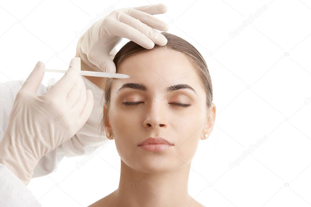 Portrait of an attractive young woman receiving botox treatment. Isolated on white background. 