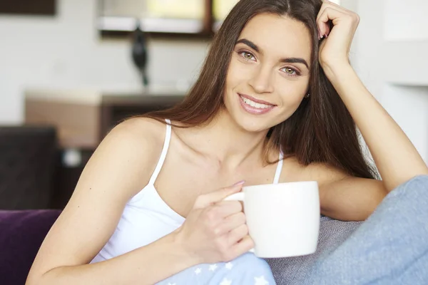 若い女性のパジャマを着て 自宅のソファでリラックスしながら彼女の朝のお茶を飲んでのクローズ アップの肖像画のショット — ストック写真