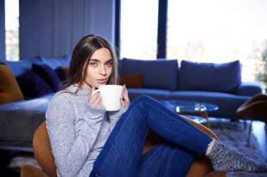 Evde kanepede rahatlatıcı çay sahip güzel genç kadın portre çekim. 