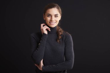 Güzel genç kadın giyiyor rulo boyun kazak ve kamera, koyu arka plan dururken bakarak yakın çekim stüdyo portre çekim. 