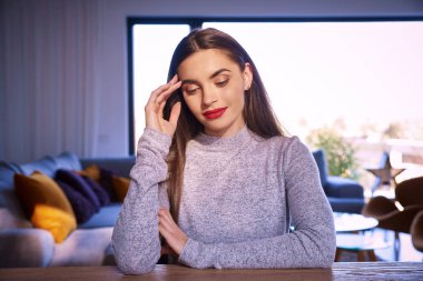 Evde masa başında otururken düşünceli arıyorum güzel genç kadın portresi. 