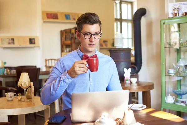 Retrato Jovem Tomando Café Enquanto Sentado Mesa Usando Seu Laptop — Fotografia de Stock