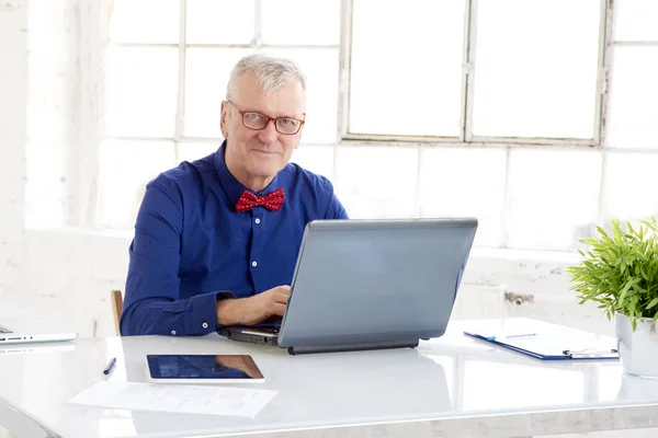 Uomo d'affari anziano che usa il suo portatile in ufficio — Foto Stock