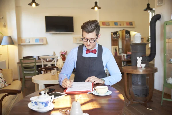 中小企業経営者の若者が机に座り カフェで書類を作成しているポートレートショット 中小企業 — ストック写真