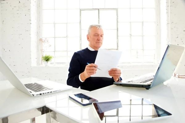 オフィスで書類を作成しながら 彼の仲間の後ろに座っている高齢のビジネスマンのショット — ストック写真
