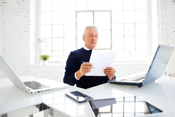 オフィスで書類を作成しながら 彼の仲間の後ろに座っている高齢のビジネスマンのショット — ストック写真