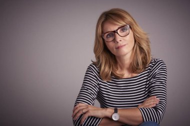 Çekici bir kadın karşı gri arka plan oturma stüdyo portresi.