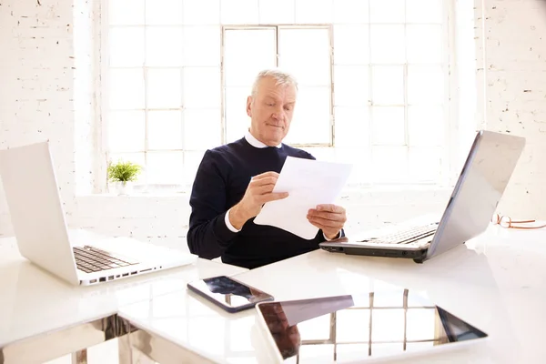 Tiro Empresário Sênior Fazendo Papelada Escritório Enquanto Sentado Frente Laptops — Fotografia de Stock