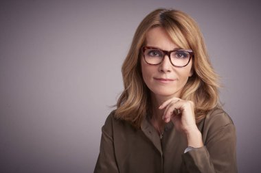 Kameraya bakarak ve açık gri renkli gülümseyen kadın orta gülümseyen yakın çekim studio portresi yaşlı. 