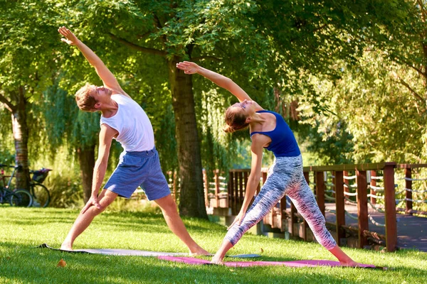 Leende par gör yoga övningar utomhus — Stockfoto