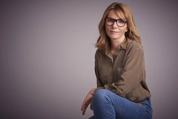 Retrato Estudio Una Atractiva Mujer Mediana Edad Sentada Frente Fondo —  Fotos de Stock