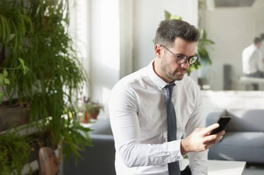 Onun cep telefonu ve kısa ofiste otururken mesaj kullanarak işadamı portre çekim. 