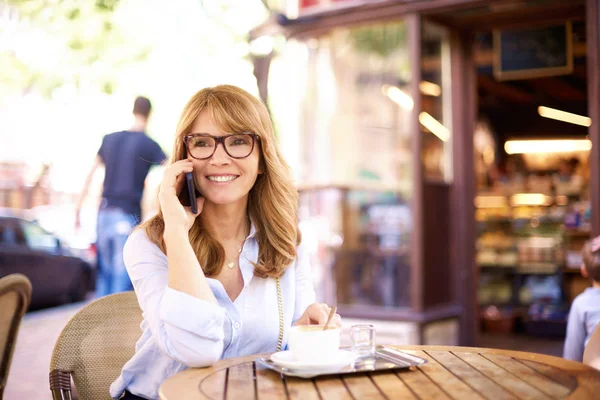 Colpo di donna di mezza età seduta in caffetteria e fare un ca — Foto Stock