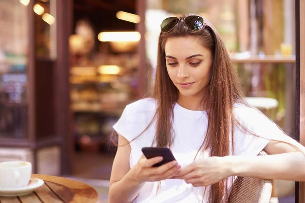 Portret van jonge vrouw zittend in café en SMS-berichten — Stockfoto