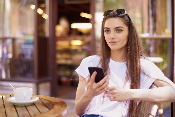 Portrait of young woman sitting in cafe and text messaging — Stock Photo, Image