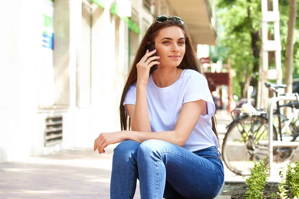 Portraitaufnahme der attraktiven jungen Frau auf der Bank sitzend und — Stockfoto