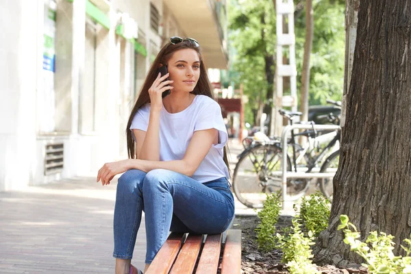 Портрет привлекательной молодой женщины, сидящей на скамейке и — стоковое фото