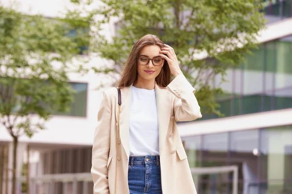 Smiling young businesswoman walking on the street near office bu — Stock Photo, Image