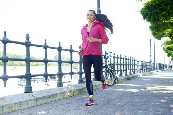 Genç bir kadının şehirde koşarken spor giydiği uzun bir çekim.. 