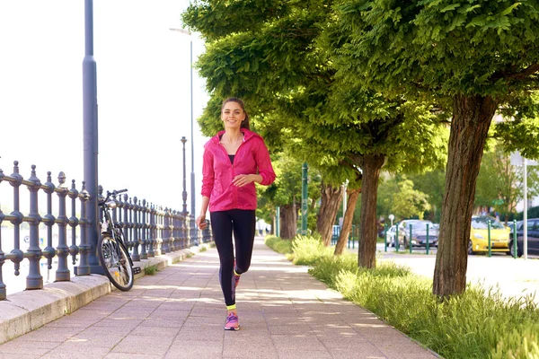 Genç bir kadının şehirde koşarken spor giydiği uzun bir çekim.. 