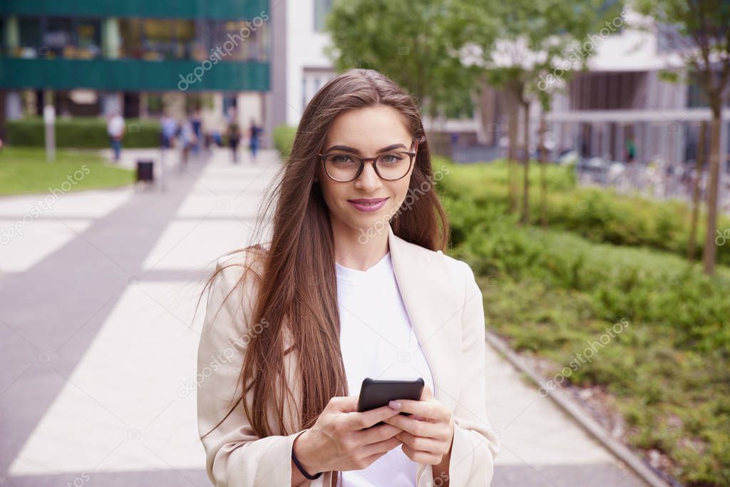 Shot of young businesswoman text messaging while walking on the street. 