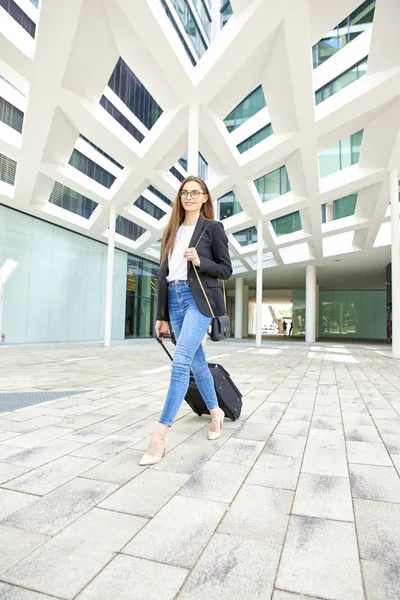 Full length shot of young businesswoman walking with her luggage after checked out from hotel.